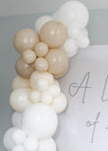 Balloon arch with beige and white balloons against a light gray background