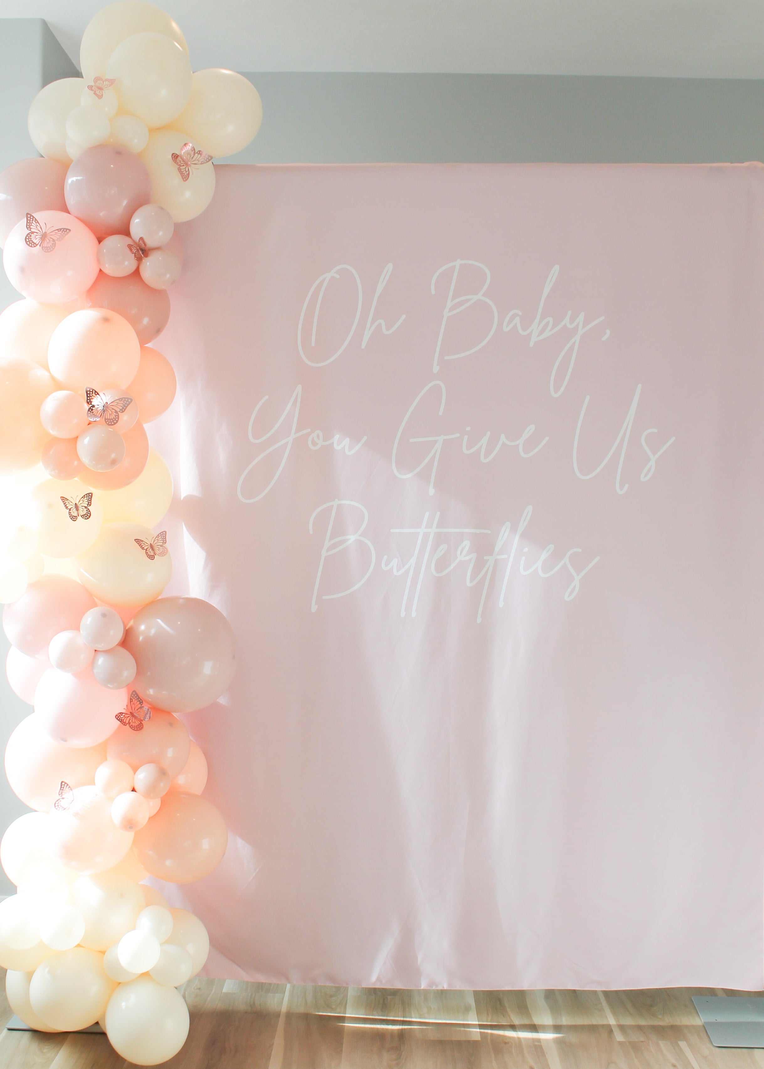 Balloon arch with pink and white balloons against a pink backdrop with text.