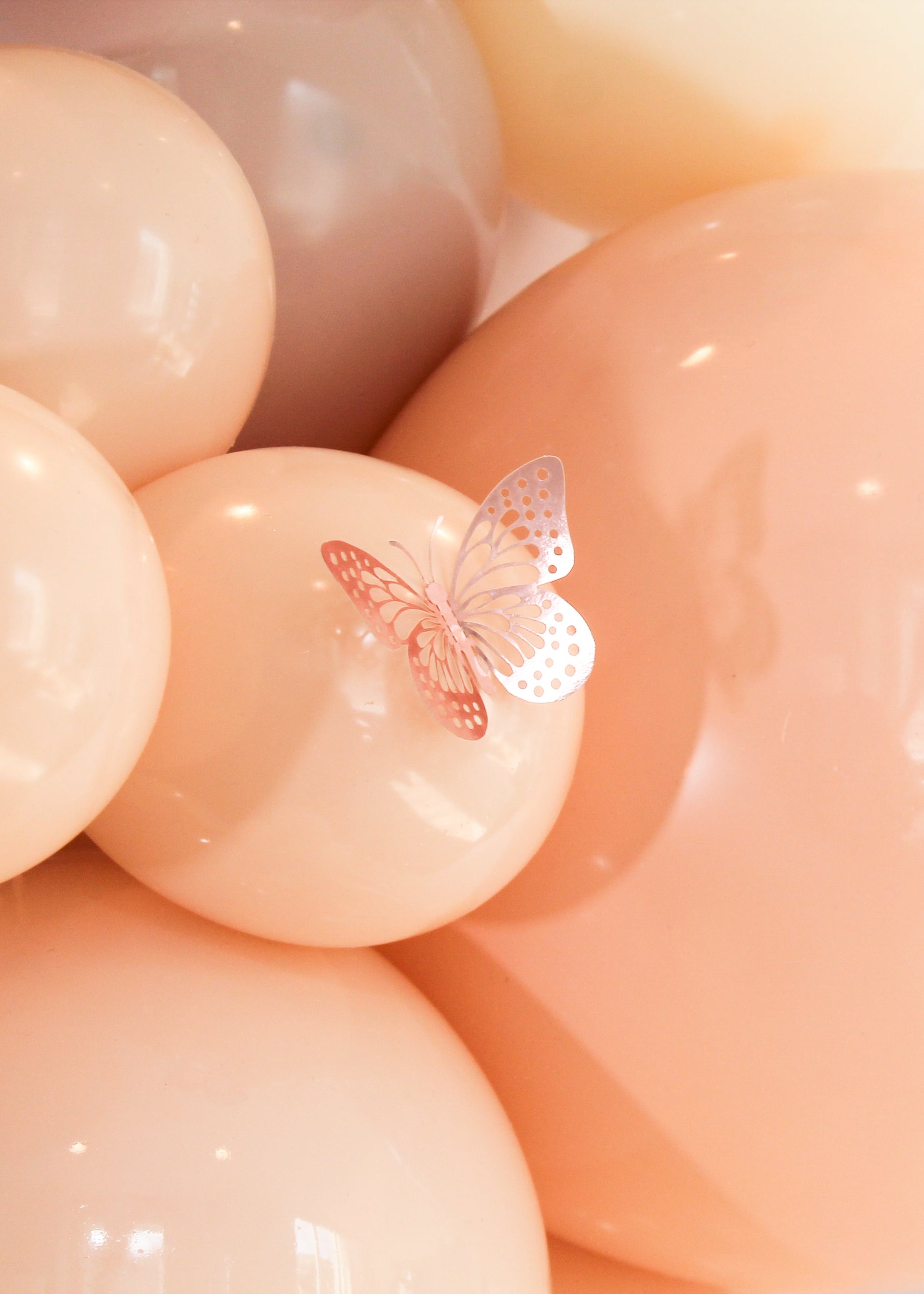 Pink balloons with butterfly decorations on a soft pink background
