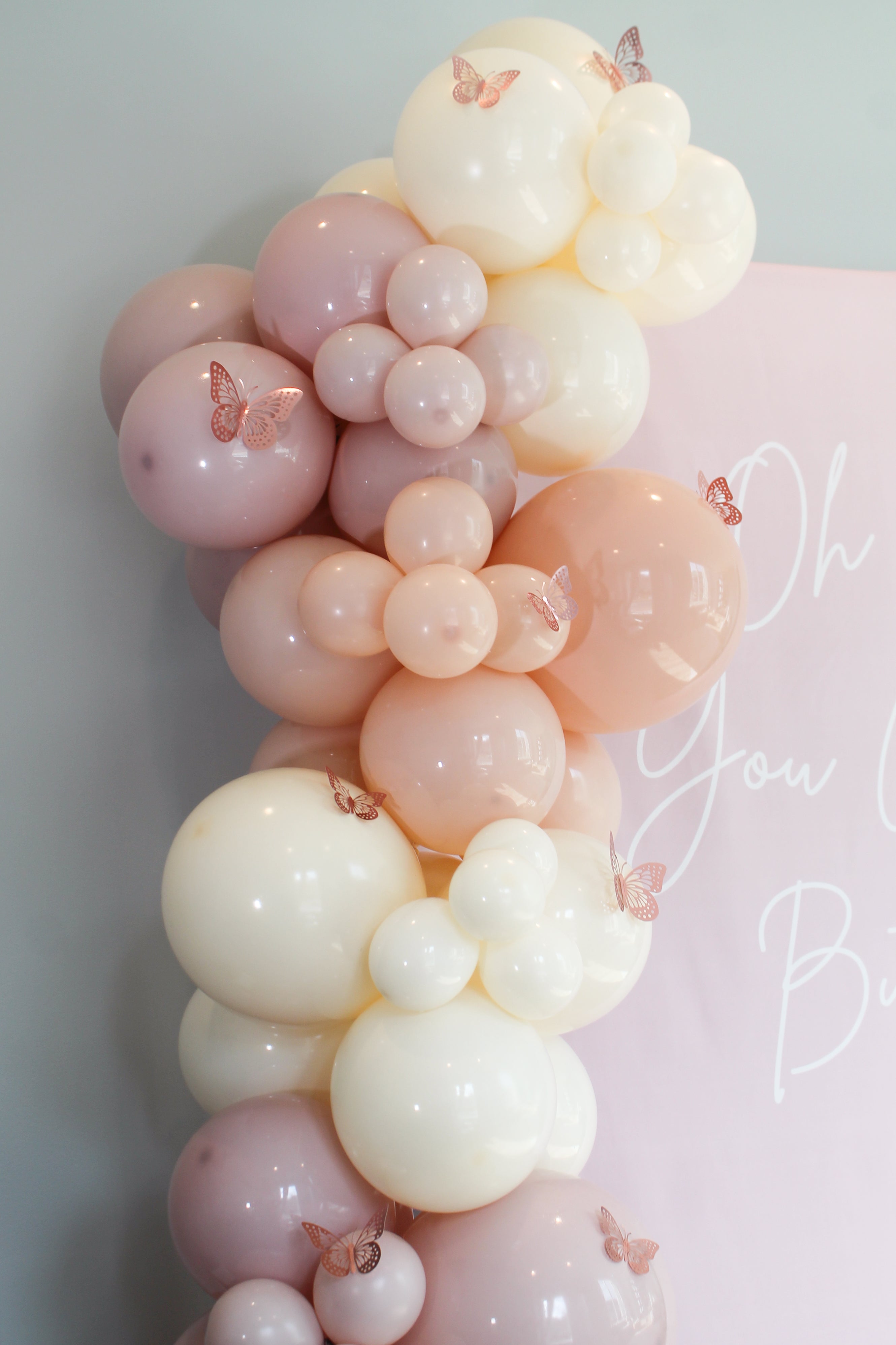 Balloon arch in soft pink and white colors with 'Oh You Are' text on a light background
