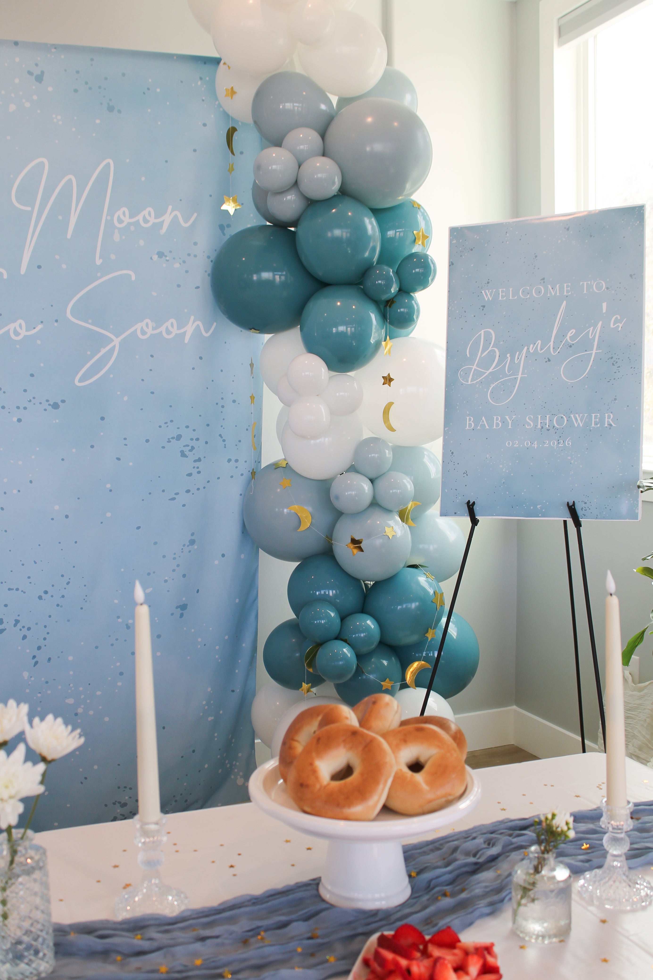Baby shower setup with balloons, donuts, and 'Welcome to Brynley's Baby Shower' sign.