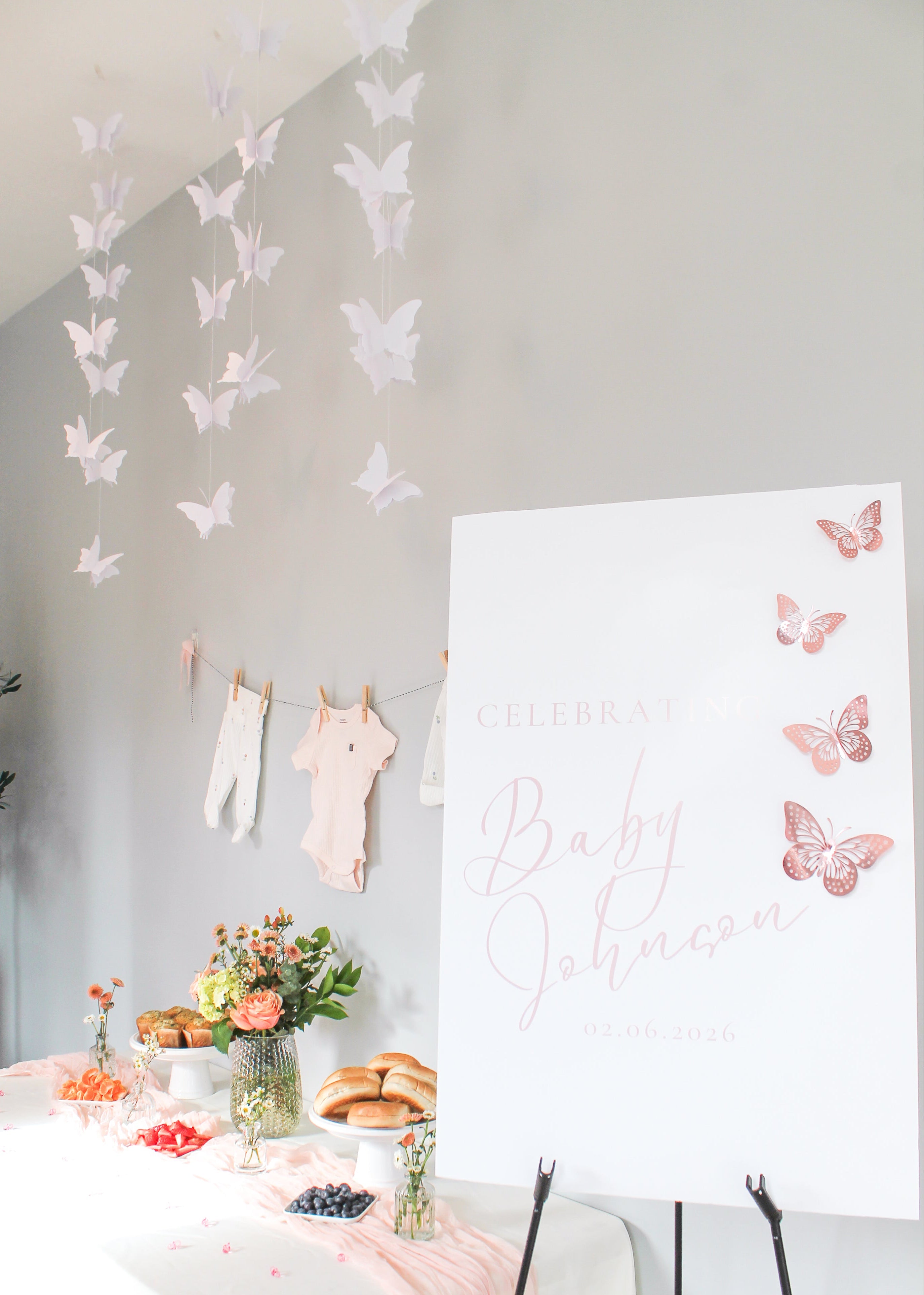 Decorative setup with butterfly decorations, a table with food, and a welcome sign with pink butterflies.
